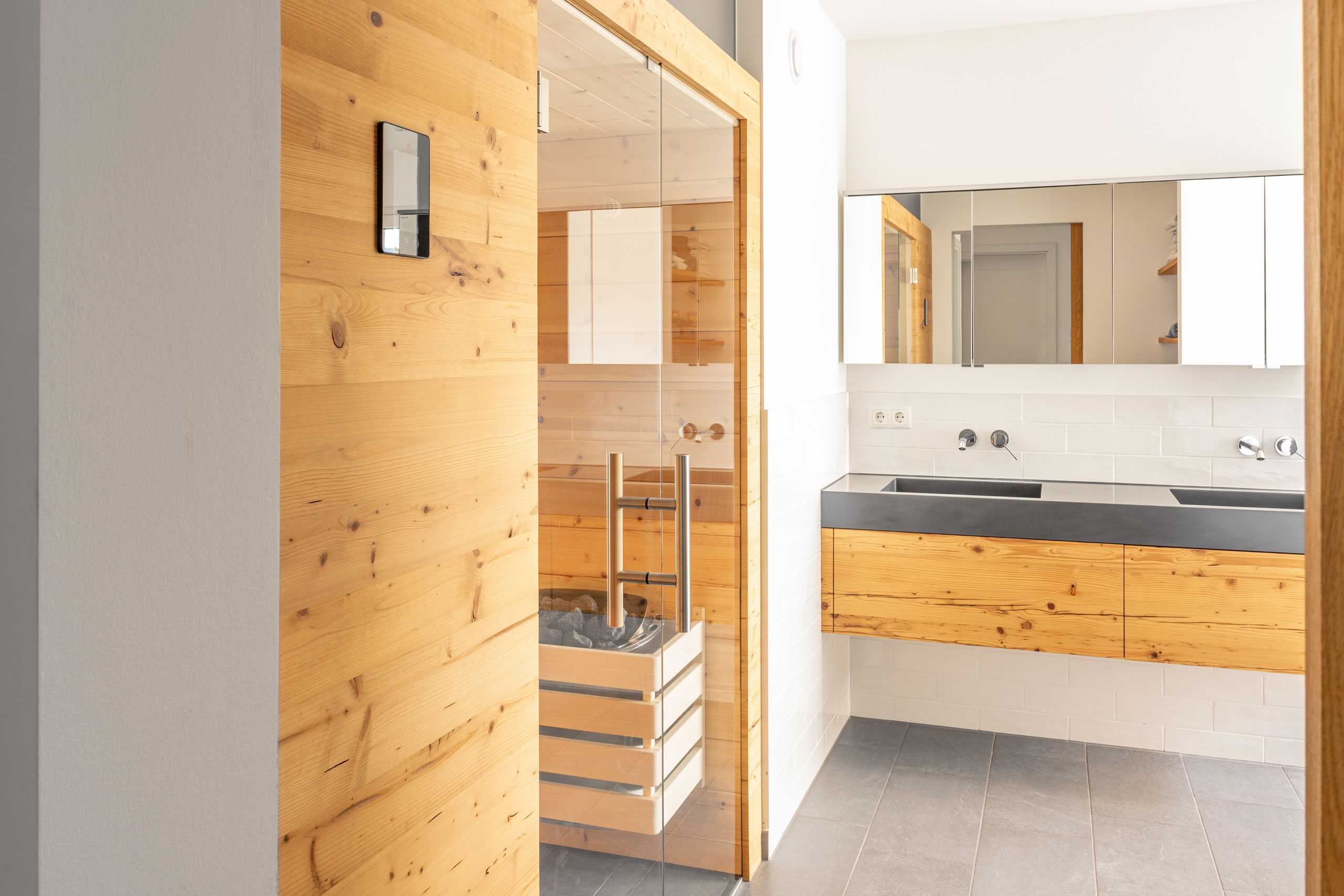 Einblick in ein Badezimmer mit Badmöbel und Sauna mit Zirbenholz Fassade Front mit schwebendem Unterschrank heller Raum Schreinerei Zimmerei Tischlerei