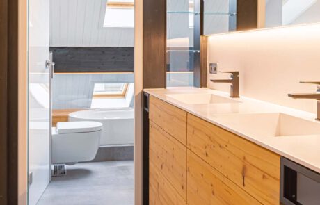 modernes Badezimmer nach Sanierung mit Corian-Becken, Waschbecken für zwei Personen, mit Holzverkleidung aus Echtholz und schwarzen Armaturen von Schreinerei in Freiburg